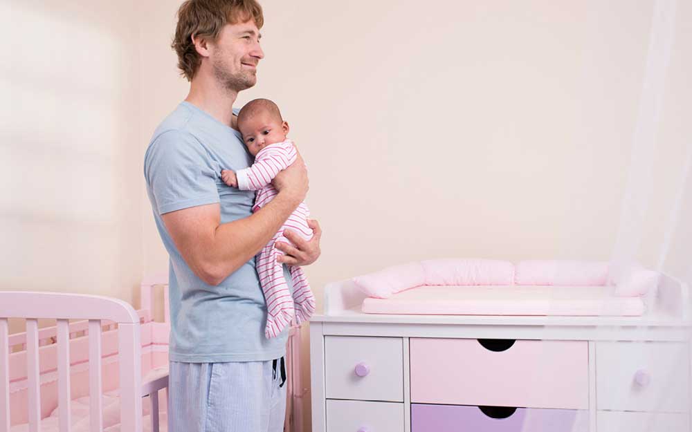 Vater hält Tochter im Babyzimmer