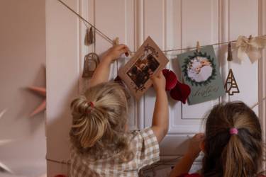 Zwei Mädchen hängen Weihnachtskarten an einer Wäscheleine auf.