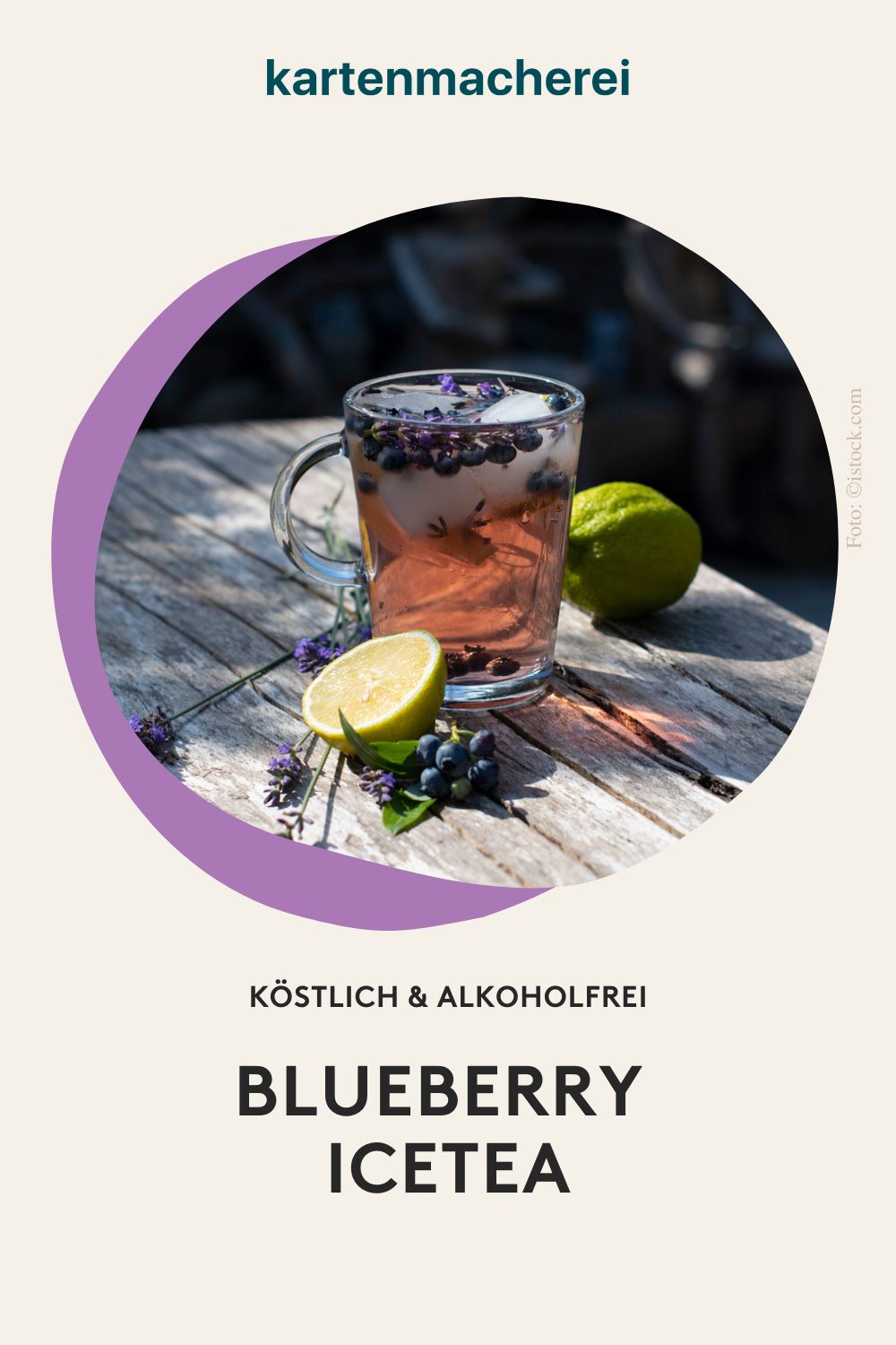 Glas mit Blaubeer-Eistee, Limetten, Lavendel und Blaubeeren auf Vintage-Holztisch im Garten
