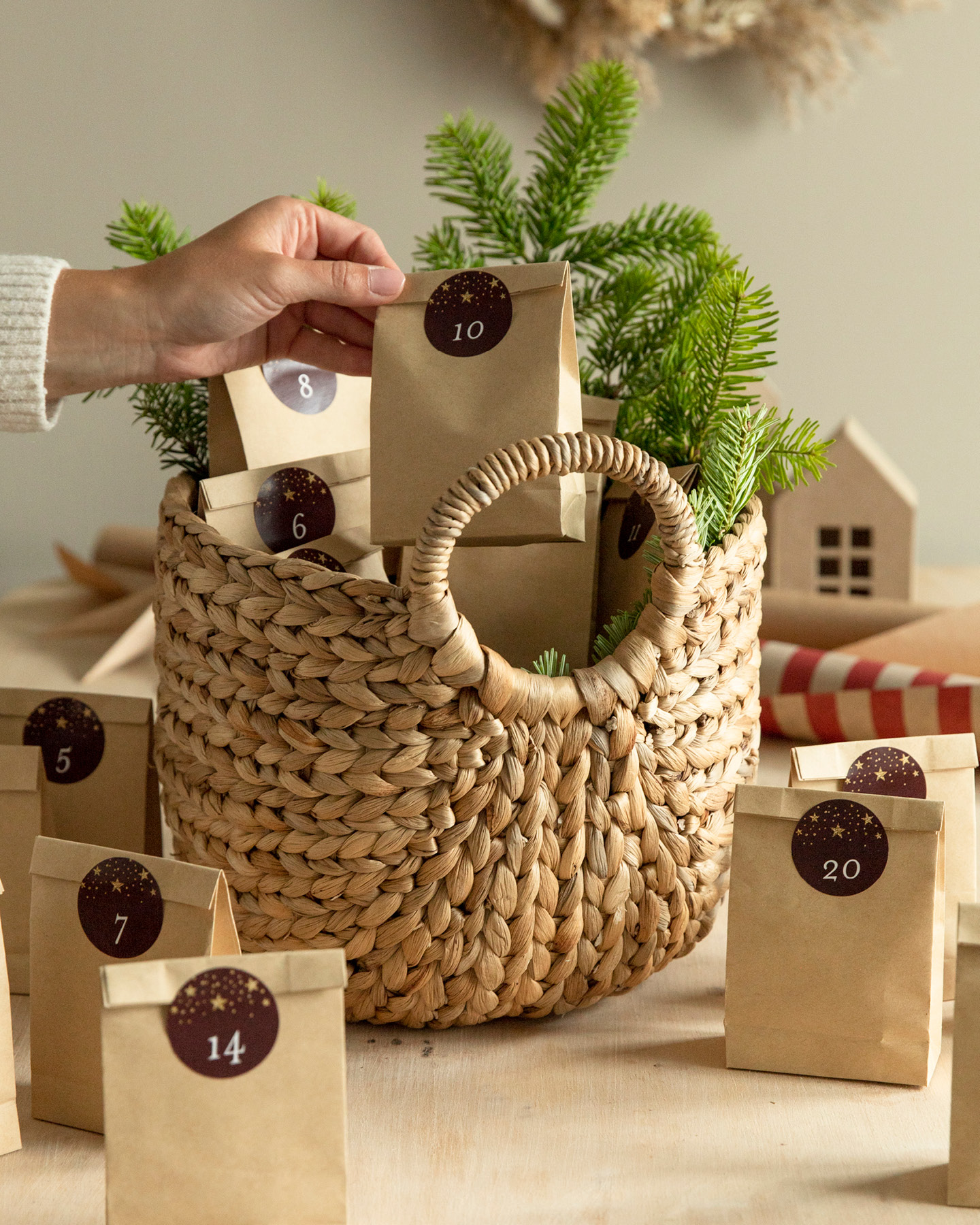 Frau nimmt eine Tüte aus Kraftpapier aus einem Weidenkorb, der als Adventskalender dient.