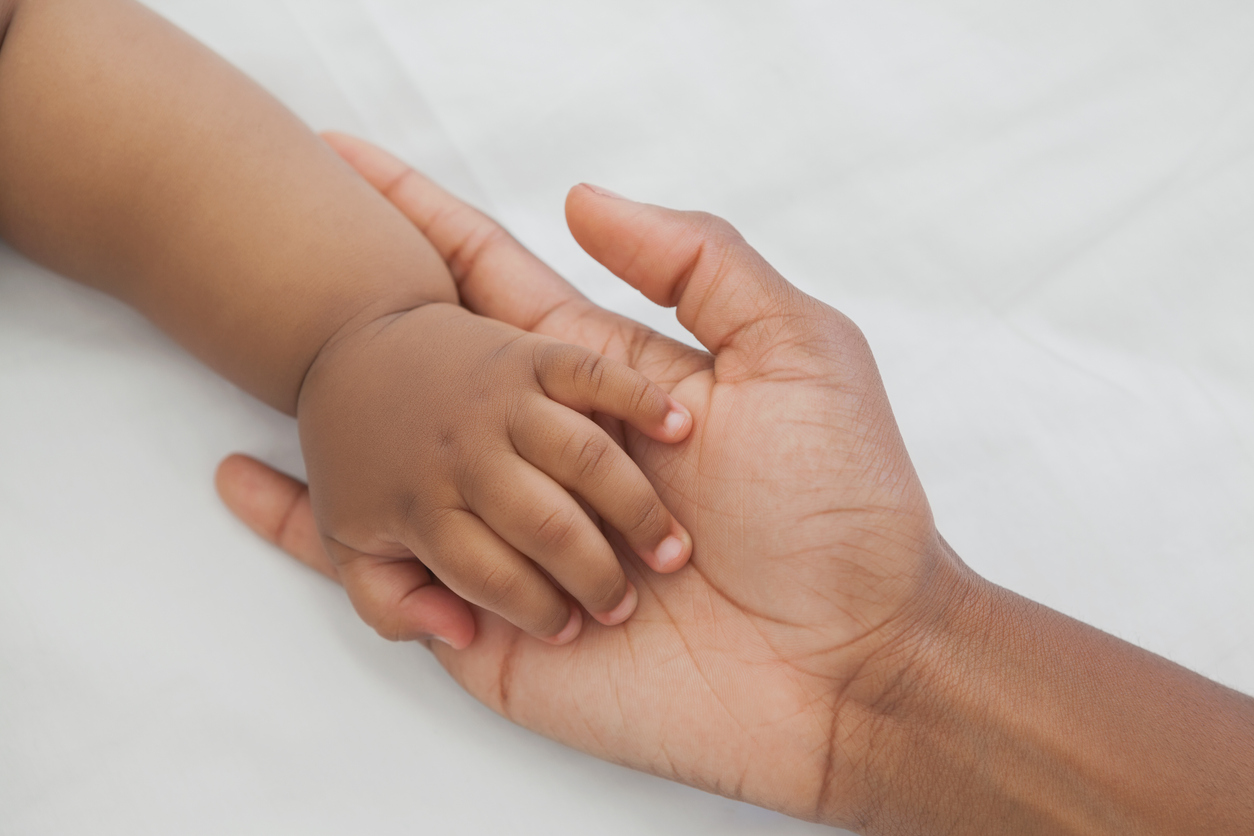Mutter hält Hand ihres Babys mit spanischem Mädchennamen
