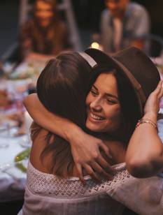 Zwei Freundinnen umarmen sich bei einer Geburtstagsparty